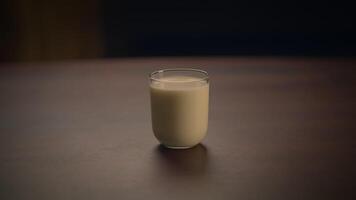 A Refreshingly Chilly Glass of Creamy Milk Resting on a Rustic Wooden Table Surface video