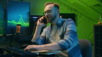 Smiling happy Caucasian broker man guy developer crypto businessman discussing mobile phone at home neon trader male work computer nighttime freelancer business good result thumb up sign stock trade video