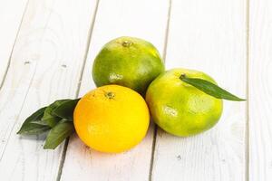 Three oranges and one lemon on a white table photo