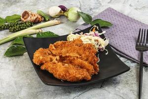 Fried chicken cutlets on a black plate with vegetables photo