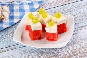 A plate of watermelon and cheese on a wooden table photo