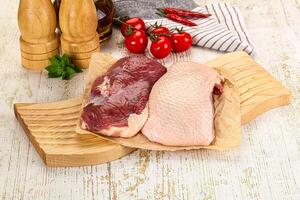 A wooden cutting board with two raw meat on it photo