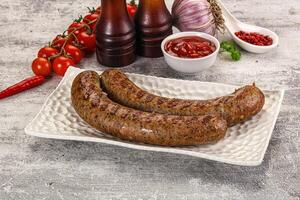 A plate with two sausages and a bottle of ketchup photo
