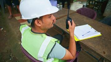 Architect has cup of coffee while talking by walkie talkie video