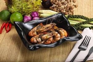 A bowl of shrimp with a fork and knife on a table photo