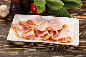 A plate of sliced ham on a wooden table photo