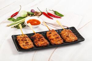 A plate with four skewers of meat on a black plate photo