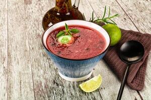 A bowl of red smoothie with a lime slice and a spoon photo