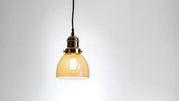 Modern pendant light with amber glass shade against a white wall. photo