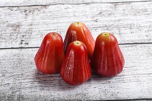 A group of red fruits sitting on a wooden table photo
