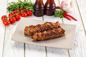 A plate with two meat skewers and a bottle of ketchup photo