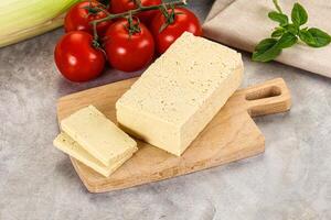 A cutting board with a block of cheese and tomatoes photo