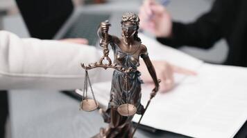 Vertical side footage of unidentified business partners negotiating clauses of joint agreement in attorneys office, focus on bronze statue of Lady Justice on table video
