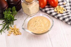 A bowl of mustard and other ingredients on a table photo