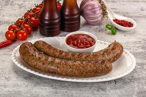 Two sausages on a plate with ketchup and tomatoes photo