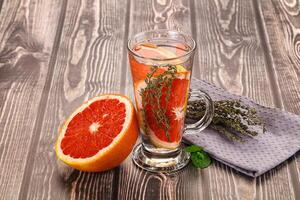A glass of water with a grapefruit and herbs photo
