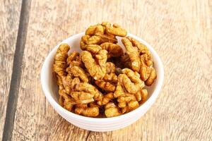 Walnuts in a bowl on a wooden table photo