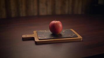 A Fresh, Bright Red Apple Resting on a Wooden Cutting Board, Ready to be Enjoyed video