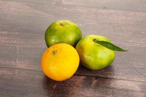 Three oranges and a lemon on a wooden table photo