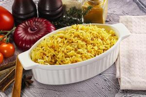 A bowl of rice with spices and vegetables on a table photo