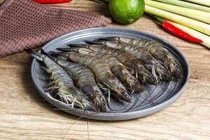 A plate of shrimp on a table with a knife and a lime photo