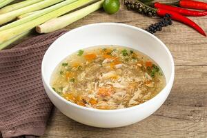 A bowl of soup with vegetables and herbs on a table photo