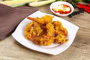A plate of fried shrimp on a table with other food photo