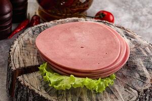 A ham sandwich on a wooden block with lettuce and tomatoes photo