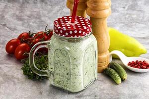 A jar of green smoothie with a red polka dot lid photo
