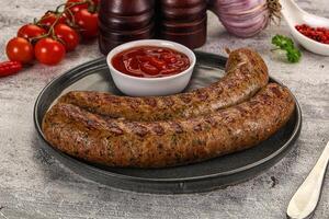 A plate with two sausages and a side of ketchup photo