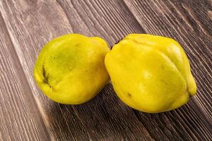 Two yellow fruits on a wooden table photo