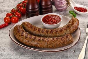 Two sausages on a plate with tomato sauce and vegetables photo