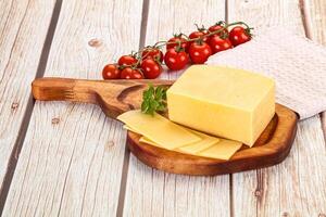 Cheese on a wooden cutting board with tomatoes and herbs photo