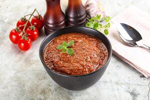 A bowl of tomato sauce with a spoon and a knife photo
