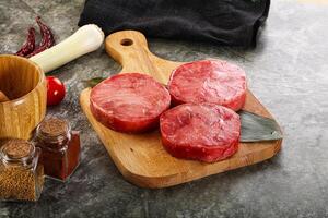 A cutting board with four steaks on it photo