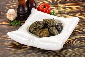 A bowl of green olives and garlic on a wooden table photo