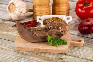 A piece of meat on a cutting board with spices and other ingredients photo