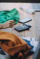 A person is using a calculator on a table with a laptop and a phone photo