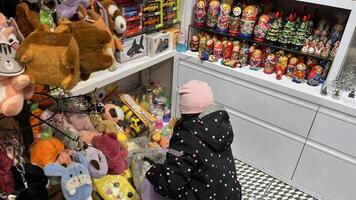 Warsaw, Poland. November 01, 2024. A little girl looking at a display of various souvenirs in a shop. The shelves are filled with colorful items photo