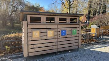 Warsaw, Poland. November 02, 2024. A wooden recycling bin with four compartments for different types of waste. Each compartment has a symbol indicating the type of waste. photo
