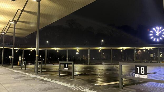 Kaunas, Lithuania. November 01. 2024. Night view of empty Kaunas bus station. There are numbered bus stops along the platform. A large clock is visible on the building photo