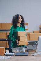 A woman is holding a stack of boxes in front of a computer photo