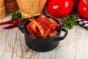 A black pot with tomatoes and peppers sitting on a table photo