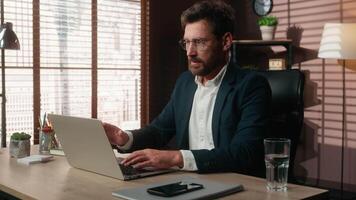 Successful smiling Caucasian middle-aged business man businessman guy male employer in office at table finish online working end computer job complete laptop task done relaxing hands behind head pause video