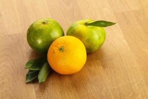 Three oranges and one lemon on a wooden table photo