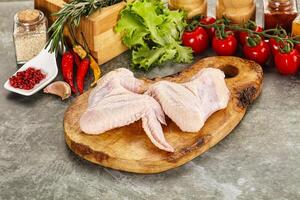 Raw chicken on a cutting board with spices and vegetables photo