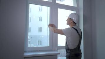 Builder in uniform makes quality control of windows installation in a new apartment. The concept of construction and repair. video