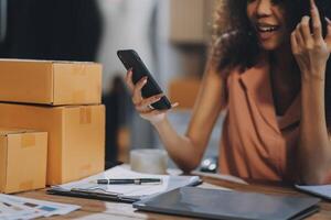 Woman using her phone while sitting at a desk with boxes and papers photo