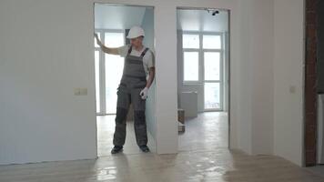 A builder in working uniform checks the size and quality of doorways in a new apartment. The concept of construction and repair. video