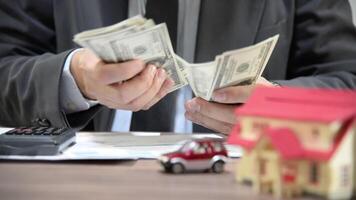 Businessman counting dollar bills at table with calculator, documents, conveying financial planning or real estate investment. video